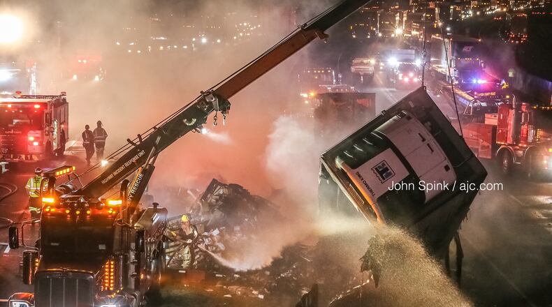 Fire crews douse a smoldering tractor-trailer Friday morning. The fire shut down all westbound lanes of I-285 just past the I-75 interchange in Clayton County for several hours.