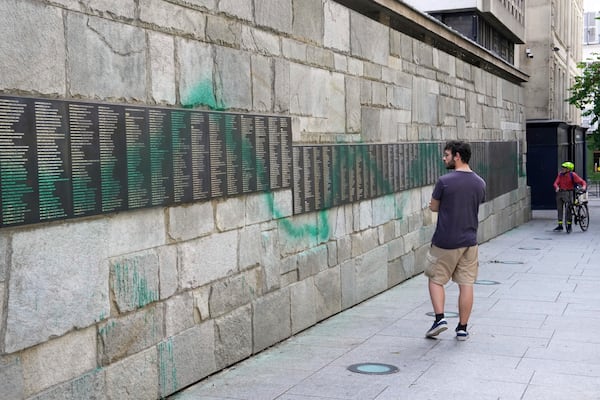 A man looks at Paris' Shoah Memorial defaced with green paint after several Jewish sites across the capital were defaced with green paint. Saturday, May 31, 2025 in Paris. (AP Photo/Aurelien Morissard)