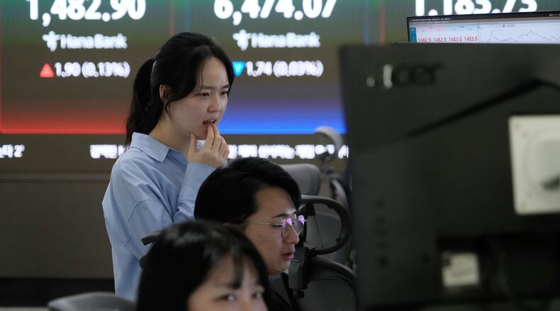 A currency trader watches monitors near a screen showing the Korea Composite Stock Price Index (KOSPI), top center, and the foreign exchange rate between U.S. dollar and South Korean won, top center left, at the foreign exchange dealing room of the Hana Bank headquarters in Seoul, South Korea, Friday, April 24, 2026. (AP Photo/Ahn Young-joon)