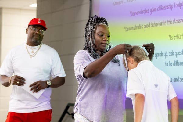 Oneida Oliver-Sanders, mother of late Army Reserve Sgt. Kennedy L. Sanders, presents an award to a fourth grade student in honor of her daughter at Waresboro Elementary School in Waycross on May 16, 2025. Shawn Sanders, Oliver-Sanders' husband, looks on.  (Arvin Temkar/AJC)