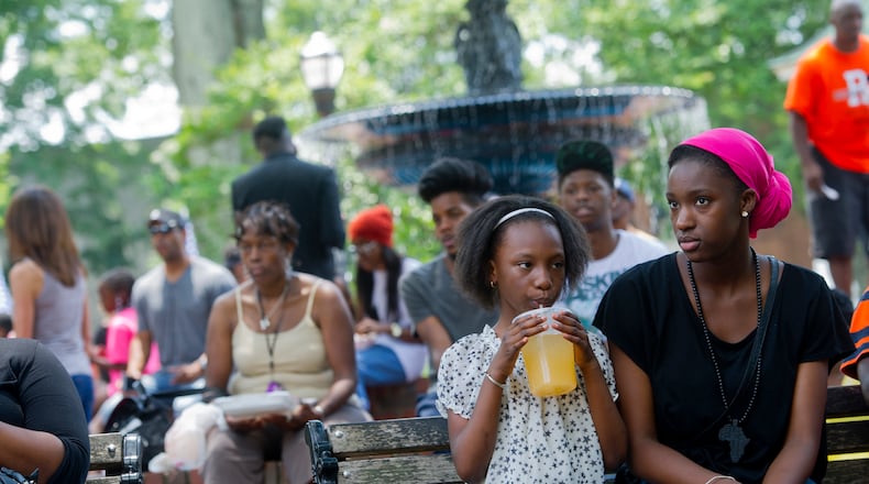 Isha Faye (right) and Oumie Faye sit on a bench as they watch the performances during the Cobb NAACP Juneteenth Celebration in Marietta Square. JONATHAN PHILLIPS / SPECIAL