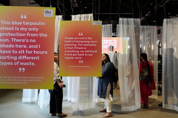 Visitors read interpretive panels highlighting the impact of heat at the Sweat and Concrete 2025 event in Bengaluru, India, Thursday, May 29, 2025. (AP Photo/Aijaz Rahi)