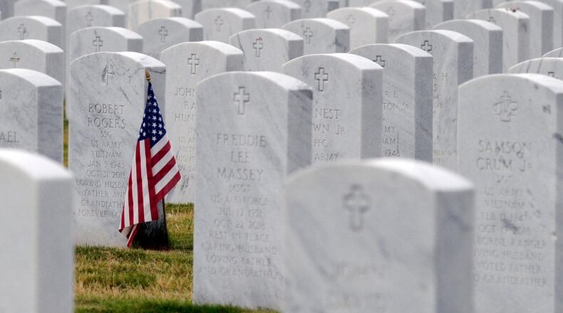 this May 22, 2020 photo, a U.S. flag decorates a veteran's grave at Alabama National Cemetery in Montevallo, Ala. Because of the coronavirus pandemic, the government has banned public ceremonies and the mass placement of flags on graves at the country's 142 national cemeteries. With almost 4.9 million people interred in the cemeteries, thousands would attend memorial events and help mark graves with flags during a typical Memorial Day weekend. (AP Photo/Jay Reeves)