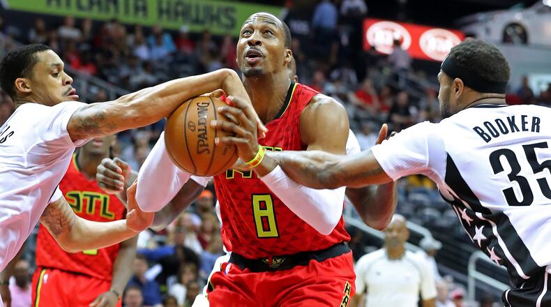 Hawks center Dwight Howard draws a foul on a rebound during a double team by Brooklyn Nets K.J. McDaniels (left) and Trevor Booker in a NBA basketball game on Sunday, March 26, 2017, in Atlanta. Curtis Compton/ccompton@ajc.com