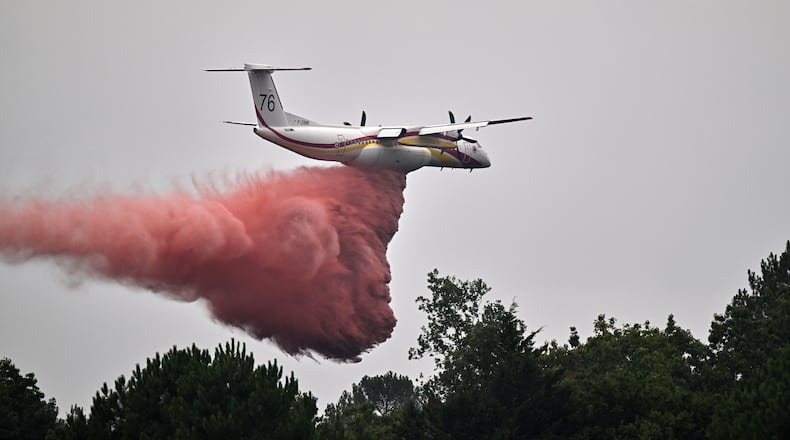 A De Havilland Canada DHC-8-400 Dash 8 operated by the French civil defense agency drops fire retardant as wildfires rage near Marcheprime, outside Bordeaux, France, Monday, July 27, 2026. (AP Photo/Emma Da Silva)