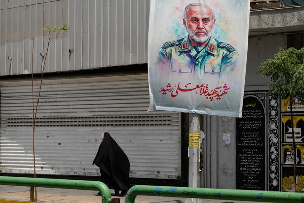 An Iranian woman walks past a banner showing head of the paramilitary Revolutionary Guard's Khatam al-Anbiya Central Headquarters Gen. Gholam Ali Rashid, who was killed in Israeli strike, at Enqelab-e-Eslami (Islamic Revolution) street in downtown Tehran, Iran, Tuesday, June 24, 2025. (AP Photo/Vahid Salemi)