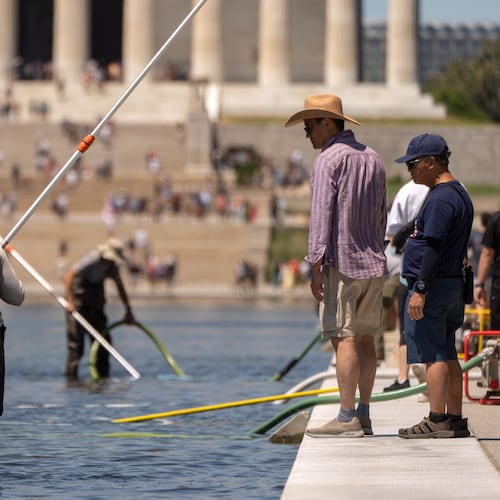 Visitors watch as National Park Service employees use vacuums to clean the Lincoln Memorial Reflecting Pool, Saturday, June 20, 2026, in Washington. (AP Photo/Mark Schiefelbein)