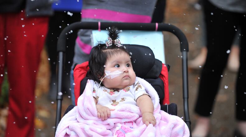 Briseida Lopez watches man made snow fall outside Children's Health Care of Atlanta Egleston. The hospital surprised patients and their families with man made snow during a weekly musical performance. Lopez, 6 months-old, is waiting for a heart transplant.