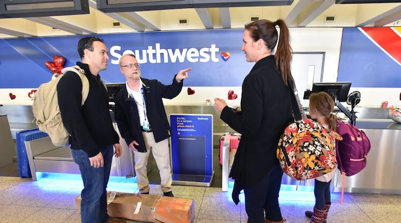Southwest Airlines staffer Henry Walters (second from left), helps customers Cameron and Jessica Chen and their daughter Katherine, 8, at the airline’s ticket counter at Hartsfield-Jackson International. Though it has fewer flights in Atlanta than AirTran did before their merger, Southwest says it focuses more on local fliers. HYOSUB SHIN / HSHIN@AJC.COM