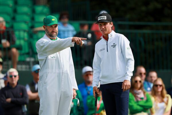 Amateur Mason Howell (right) talks with his caddie, Brookwood golf coach Jimmy Gillam, before a putt on the first green during a practice round at the Masters on Monday, April 6, 2026, in Augusta. (Jason Getz/AJC) 