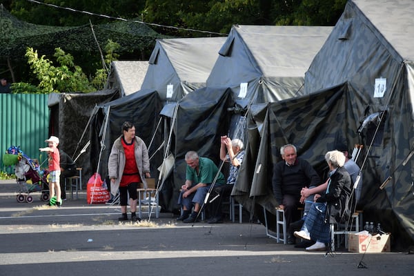 FILE - People sit next to tents at a temporary residence center in Kursk, Russia, after being evacuated due to fighting between Russian and Ukrainian forces in the Kursk region on Monday, Aug. 12, 2024. (AP Photo, File)