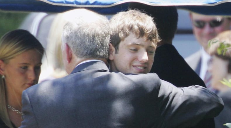 In this June 29, 2006, file photo, John Ramsey hugs his son, Burke, facing camera, at the graves of his wife, Patsy, and daughter JonBenet, during services for his wife at the St. James Episcopal Cemetery in Marietta, Ga. A judge has declined to dismiss a $750 million defamation lawsuit filed against CBS by JonBenet Ramsey’s brother, Burke Ramsey. (AP Photo/Ric Feld, File)