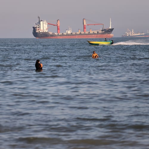 Residents swim in the waters of the Strait of Hormuz as a small motorboat passes cargo ships and other commercial vessels offshore near Bandar Abbas, Iran, Wednesday, June 17, 2026. (Amirhosein Khorgooi/ISNA via AP)