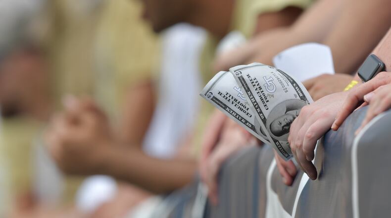 A Georgia Tech fan holds fake money printed  with the portrait of Georgia Tech head coach Geoff Collins in the first half at Bobby Dodd Stadium on Saturday, Sept. 14, 2019.
