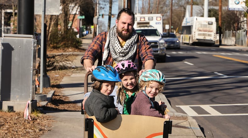 Brendan Horgan rides his bike with his children (left to right) on Jan. 31, 2024, in a school zone where cameras have been installed to prevent speeding. (Natrice Miller/The Atlanta Journal-Constitution)
