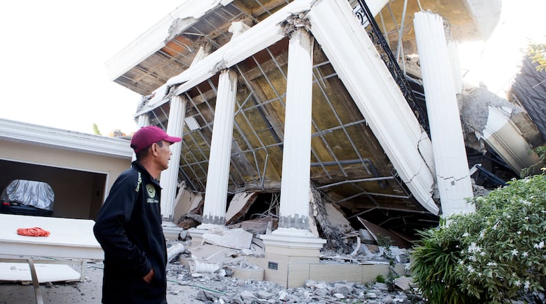 A man examines a building that collapsed during an earthquake in Reo, East Nusa Tenggara province, Indonesia, Monday, Aug. 17, 2026. (AP Photo/Firdia Lisnawati)