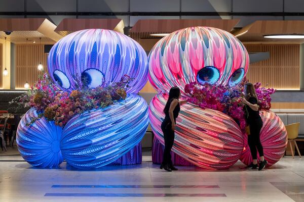 Flowers are arranged in the arms of one of the "aliens" in Eness' art installation "Stem by Stem – Alien Boy Gives Me Flowers,” which has previously been installed in multiple locations around the globe and will open in Woodruff Park on Feb. 13. (Courtesy of Gavin Jowitt)