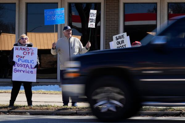 People hold signs during a demonstration outside of the United States Postal Service in Arlington Heights, Ill., Thursday, March 20, 2025. (AP Photo/Nam Y. Huh)