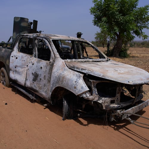 In this photo released by the Kebbi State Government, a man inspects a burned military vehicle following a late Tuesday ambush by armed militants in Shanga, Kebbi, northern Nigeria, Wednesday, March. 25, 2026. (Kebbi State Government via AP)