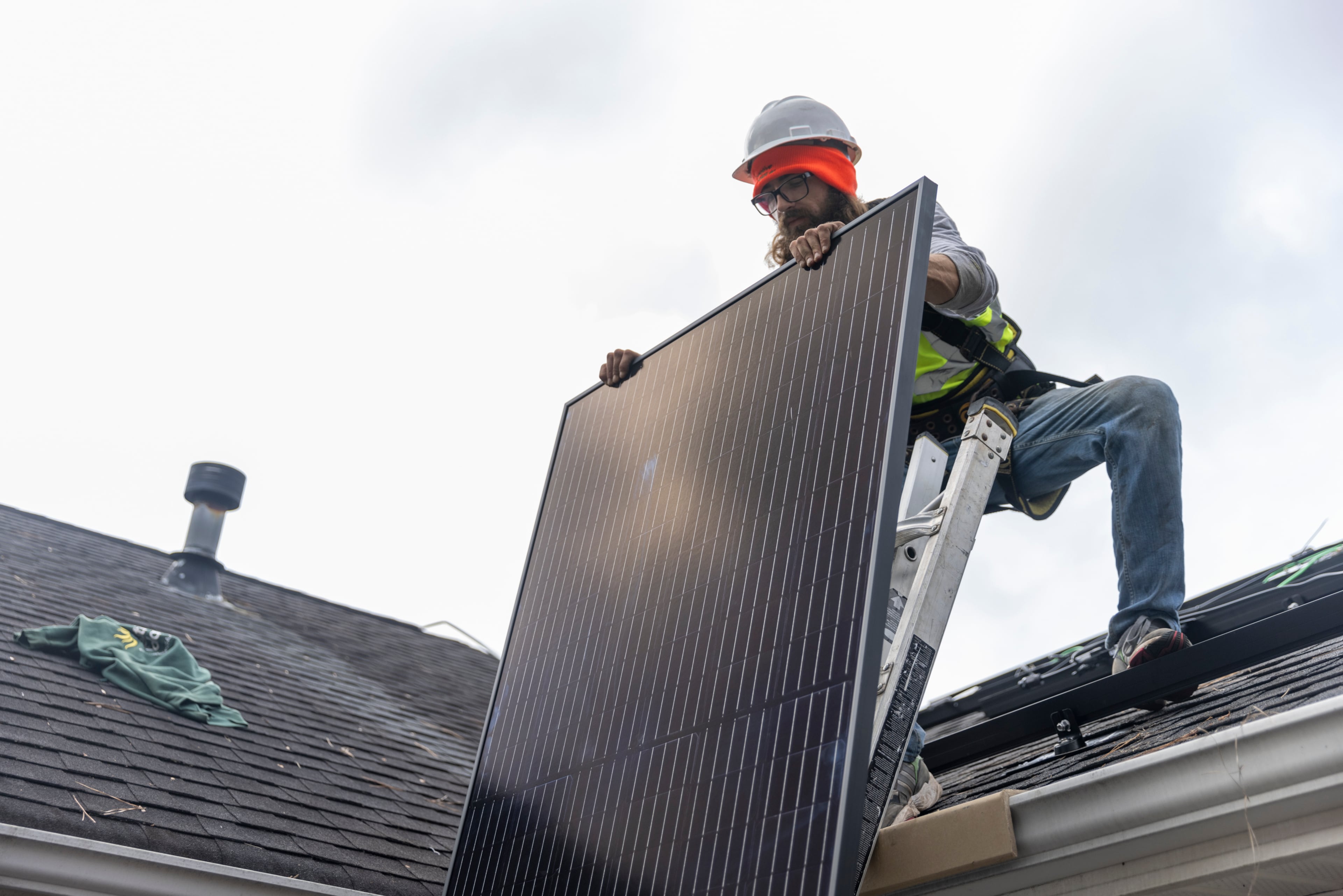 Joe McClain, an installer for Creative Solar USA, moves solar panels onto the roof of a home in Ball Ground, Georgia, on December 17th, 2021. (Nathan Posner for The Atlanta Journal-Constitution)