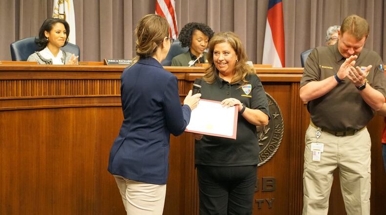 Cobb County Commissioner Keli Gambrill (left) presents a certificate of recognition to Cobb County 911 operator Dana Bell during a County Commission meeting Monday, March 21, 2022. Bell was recognized for answering more than 20,000 calls in less than a year, breaking the county's record for most calls handled.