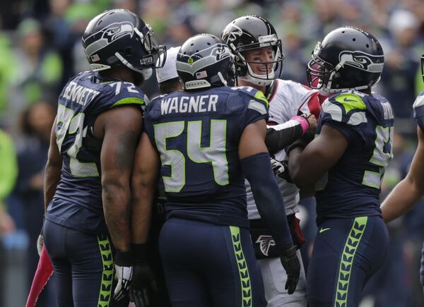 Atlanta Falcons quarterback Matt Ryan, second from right, has a mild exchange of words with Seattle Seahawks' Michael Bennett, left, Bobby Wagner (54) and Cliff Avril (56), during an NFL football game against the Atlanta Falcons, Sunday, Oct. 16, 2016, in Seattle. (AP Photo/Stephen Brashear)