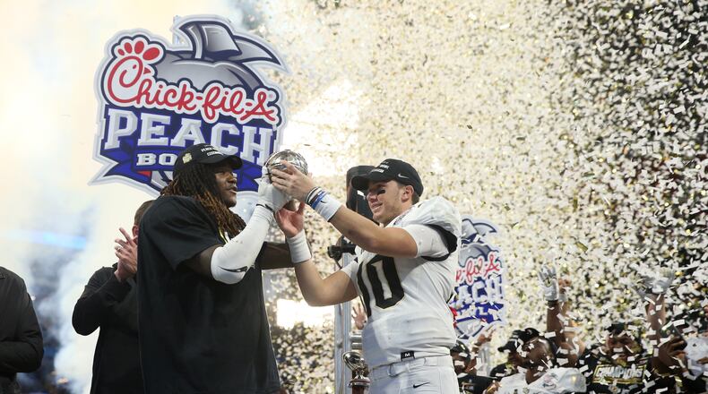 UCF Knights linebacker Shaquem Griffin (18) and quarterback McKenzie Milton (10) celebrate with the trophy after their win against the Auburn Tigers during the Chick-fil-a Peach Bowl at the Mercedes-Benz Stadium Monday, January 1, 2018, in Atlanta. The UCF Knights won 34-27. PHOTO / JASON GETZ