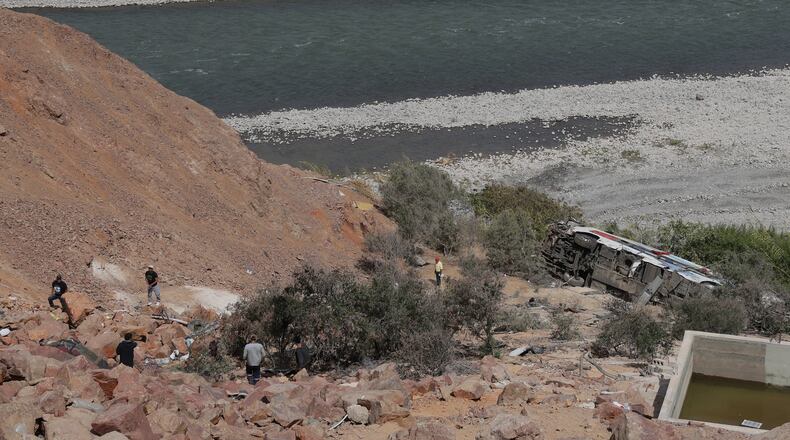 People walk by a passenger bus after its deadly crash with another vehicle in Arequipa, Peru, Wednesday, Nov. 12, 2025. (AP Photo/Kiara Tapia)