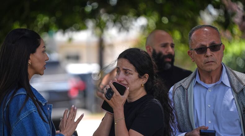 People stand behind police tape at the scene of a shooting outside the Islamic Center of San Diego Monday, May 18, 2026, in San Diego. (AP Photo/Gregory Bull)