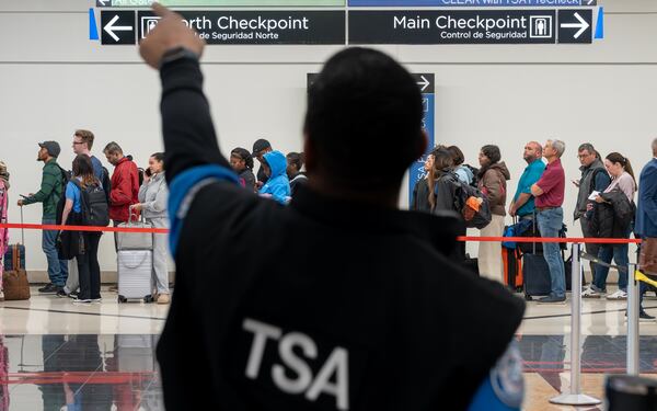 A Transportation Security Administration officer helps a traveler find the right security line at Hartsfield-Jackson Atlanta International Airport. (Ben Hendren for the AJC)