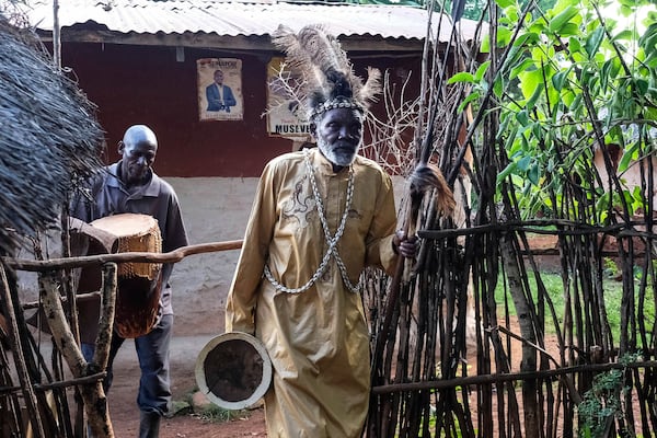 Seer Atukung Tafala, front, walks inside his igloo-like shrine in Kampala, Uganda Saturday, June 21, 2025. (AP Photo/Hajarah Nalwadda)