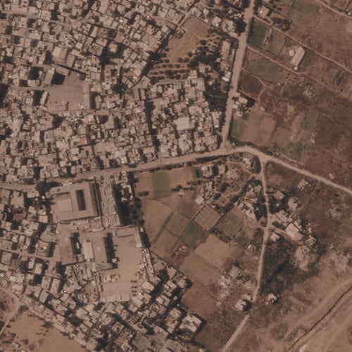 This satellite image from Planet Labs PBC shows a section of an earthen barrier being built by the Israeli military, right side of image moving top to bottom, in the central Gaza Strip, July 1, 2026. At left is the Maghazi refugee camp, and on the other side are homes demolished by the military. (Planet Labs PBC via AP)