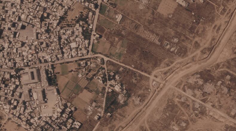 This satellite image from Planet Labs PBC shows a section of an earthen barrier being built by the Israeli military, right side of image moving top to bottom, in the central Gaza Strip, July 1, 2026. At left is the Maghazi refugee camp, and on the other side are homes demolished by the military. (Planet Labs PBC via AP)