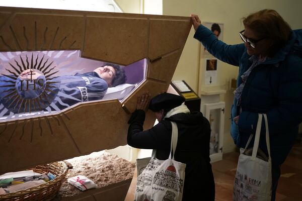 People pray in front of the body of Carlo Acutis, a 15-year-old Italian boy who died in 2006 of leukemia and beatified in 2020, in the Santa Maria Maggiore church in Assisi, Italy, Wednesday, April 2, 2025. (AP Photo/Alessandra Tarantino)