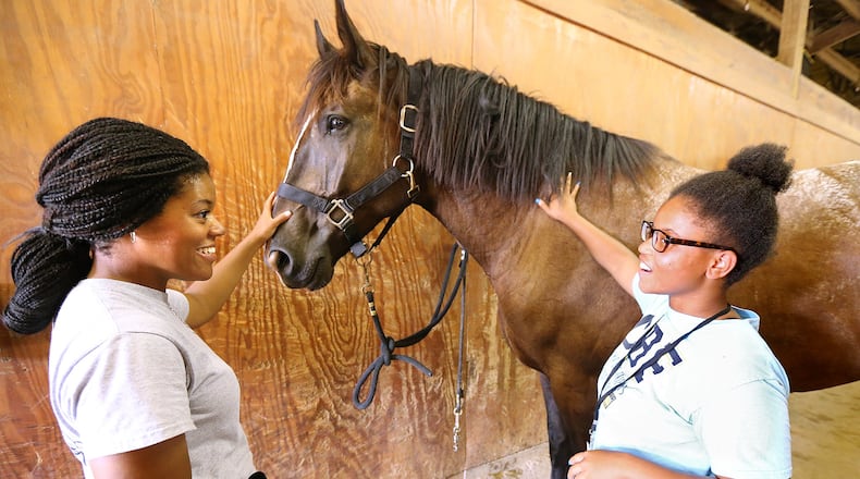 Marsharkia Perry, from the Thomasville Center of Hope Boys and Girls Club, meets her horse Magnum after teaming up with her mentor officer Rackella Johnson at the Atlanta Police Department Mounted Patrol while officers engage children through a mentoring program to strengthen youth-police relations on July 13, 2016, in Atlanta. CURTIS COMPTON / CCOMPTON@AJC.COM
