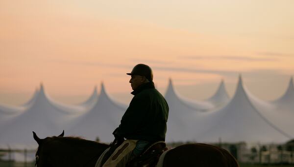 FILE - Trainer D. Wayne Lukas sits atop his horse as he watches morning workouts against the backdrop of a large tent set up in the infield before sunrise at Churchill Downs in Louisville, Ky., April 25, 2009. (AP Photo/Ed Reinke, file)