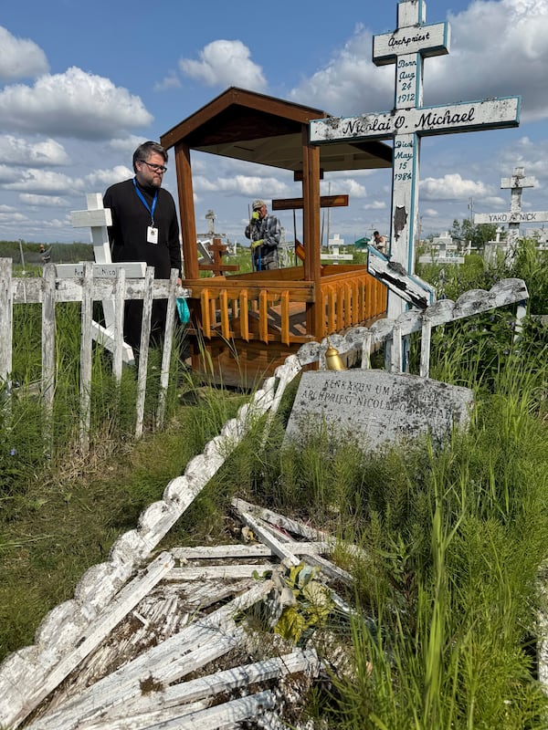 Deacon Michael Lucius of Toronto visits the gravesite of Matushka Olga Michael in Kwethluk, Alaska, on June 18, 2025, a day before she became the first female Orthodox saint in North America. In the foreground is the grave of Olga's husband, Nicolai Michael, who was a priest in Kwethluk. (AP Photo/Mark Thiessen)