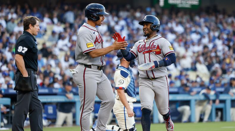 Atlanta Braves designated hitter Drake Baldwin, center left, greets teammate Ozzie Albies, center right, after they scored off a single hit by Braves' Matt Olson (not shown) during the second inning of a baseball game against the Los Angeles Dodgers, Saturday, May 9, 2026, in Los Angeles. (AP Photo/Caroline Brehman)