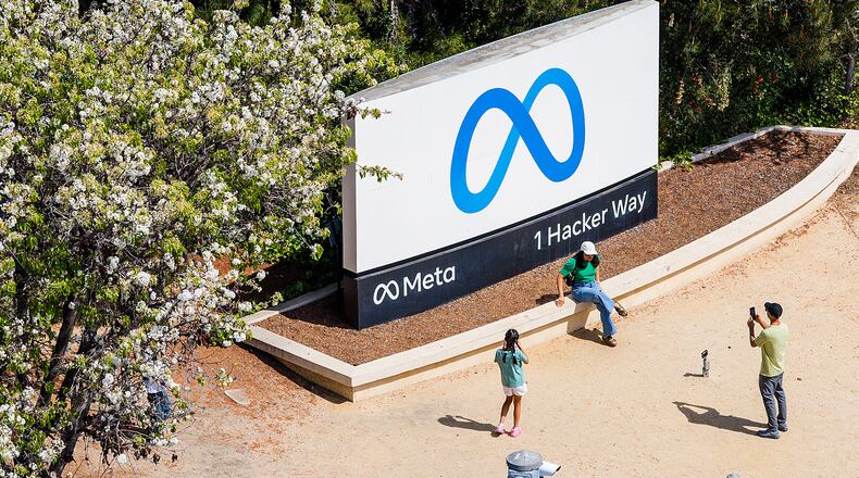 FILE - Visitors take photos at a sign outside Meta headquarters March 26, 2026, in Menlo Park, Calif. (AP Photo/Noah Berger, File)
