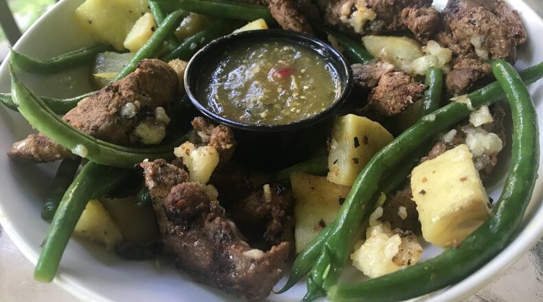 Café Lily's signature dish, Pinchitos, brings chargrilled Spanish-spiced lamb tenderloin with sauteed white sweet potatoes, green beans, picante salsa verde and Manchego cheese. Ligaya Figueras / ligaya.figueras@ajc.com