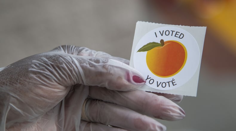 05/18/2020 - Lawrenceville, Georgia - A n early voter, who wore gloves to cast their ballot, shows off their sticker at the Gwinnett County Voter Registration and Elections Office in Lawrenceville, Monday, May 18, 2020. Early voting began May 18 and will last three-weeks, ended June 5. Georgia’s Election Day is Tuesday, June 9.(ALYSSA POINTER / ALYSSA.POINTER@AJC.COM)