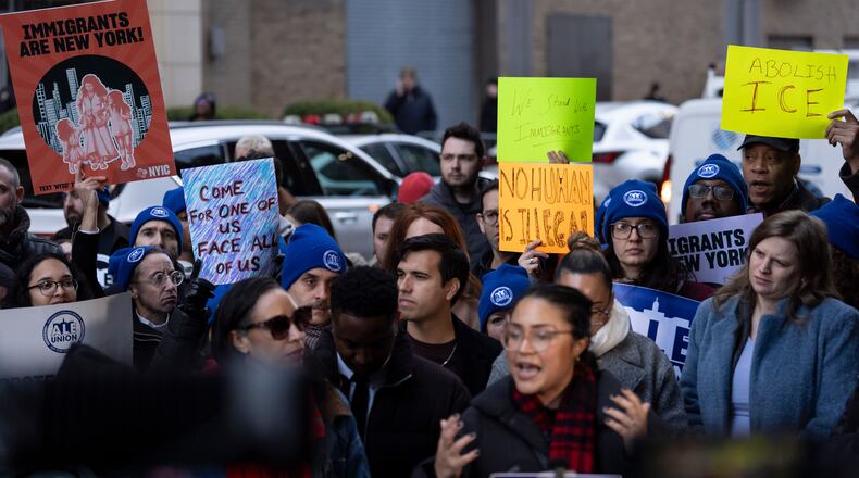 People raise signs during a news conference outside Greater New York Federal Building, Tuesday, Jan. 13, 2026, in New York. (AP Photo/Yuki Iwamura)