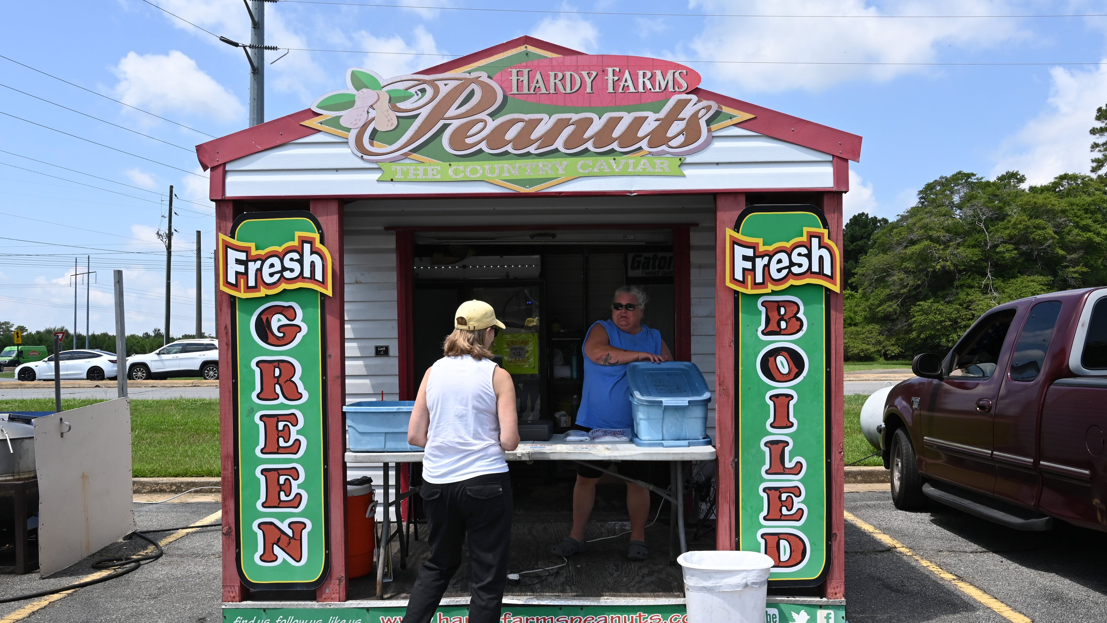 Timmi Moore, peanut stand manager, helps customer Leigh Ann Edenfield at one of Hardy Farms Peanuts’ roadside stands in Warner Robins. Hardy Farms Peanuts, which also sells to supermarkets, has cornered the Middle Georgia roadside peanut stand market. (Hyosub Shin/AJC)
