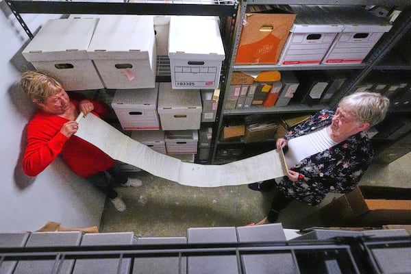 Historian Jennifer Cromack, left, and Rev. Diane Badger unfurl a recently found, 178-year-old anti-slavery scroll which was found in a storage box at Grotonwood, the home mission of The American Baptist Churches of Massachusetts, Thursday, June 26, 2025, in Groton, Mass. (AP Photo/Charles Krupa)