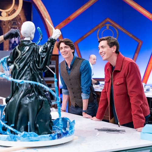 This image released by Food Network shows hosts Oliver Phelps, right, and James Phelps, watching contestants Katie Bonzer, left, and Jujhar Mann on the set of the competition series "Harry Potter: Wizards of Baking." (Anders Krusberg/Food Network via AP)