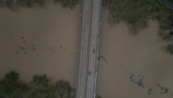 An aerial view of debris floating down the Kentucky River as vehicles drive over a bridge Saturday, April 5, 2025, in Frankfort, Ky. (AP Photo/Jon Cherry)
