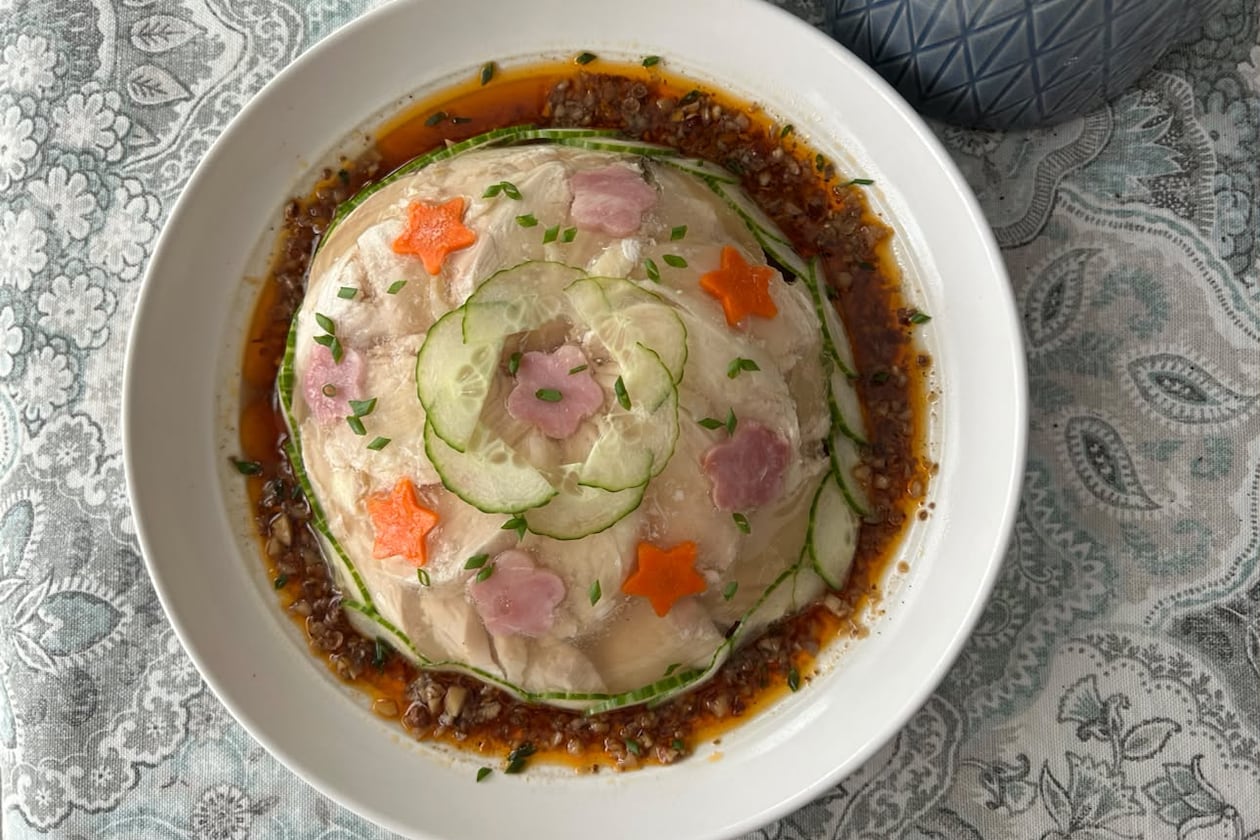 A plate sits on the table with a domed aspic studded with cucumber circles and star designs.