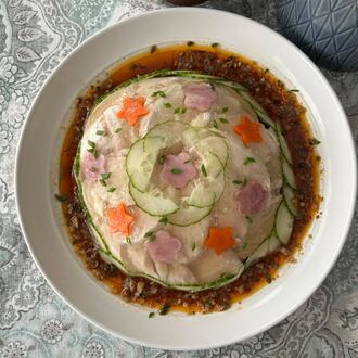 A plate sits on the table with a domed aspic studded with cucumber circles and star designs.