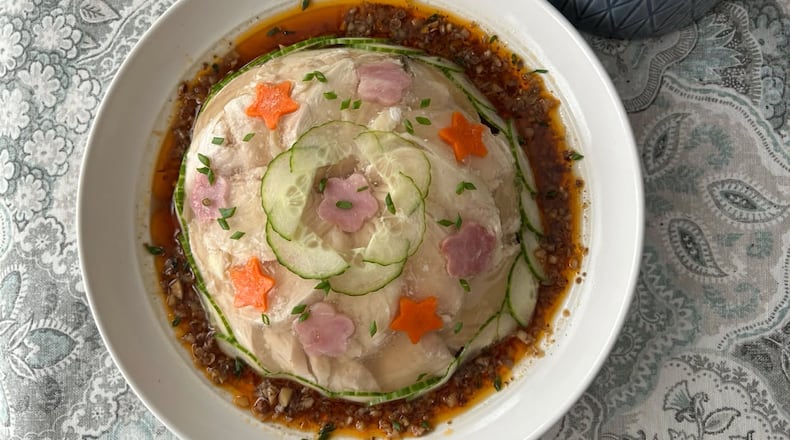 A plate sits on the table with a domed aspic studded with cucumber circles and star designs.