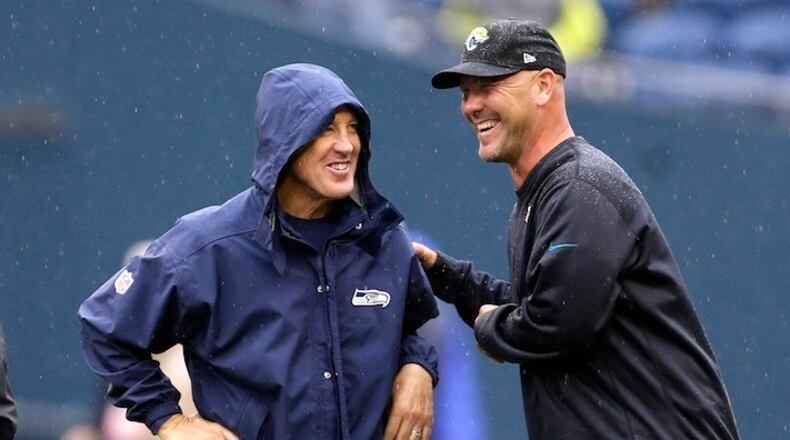In this Sept. 22, 2013, file photo, Seattle Seahawks head coach Pete Carroll, left, and Jacksonville Jaguars head coach Gus Bradley talk in the rain before an NFL football game in Seattle. The scheme that carried the Seahawks to consecutive Super Bowls (2013-14) has become increasingly popular around the league. It helped Atlanta get to the big game last year and was the catalyst for Jacksonville's stunning turnaround this season. (AP Photo/Ted S. Warren, File)